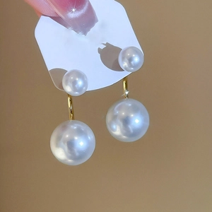 Dettaglio di orecchini con doppia perla e placcatura in oro 14k dal design a C