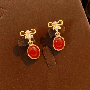Detailliertes Makro von Vintage Gold-Schleifenohrringen mit roten Harzanhängern