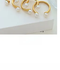 Detail of U-shape gold-plated titanium steel earrings with white pearls on a minimalist base