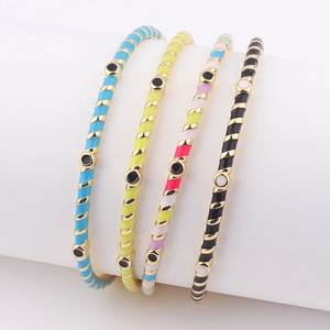 Fashionable enamel striped bangles with evil eye detail on a white jewelry display stand