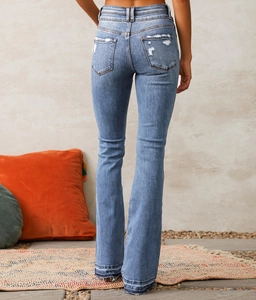 Close-up of distressed back pocket detail on high-waisted vintage washed blue flare jeans