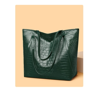Detailed view of dark green faux crocodile leather texture on a premium tote bag