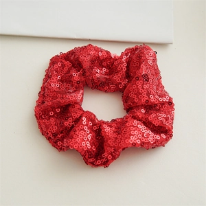 Close-up of red sequined hair scrunchie showing detailed shiny texture and fabric folds