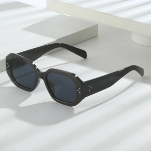 Close-up of black hexagonal sunglasses with rivet accents and dark grey UV lenses