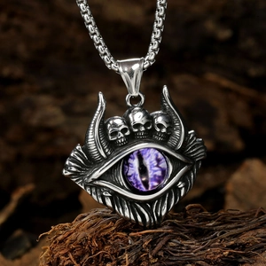 Macro shot of silver skull pendant with purple devil eye on dark wood background