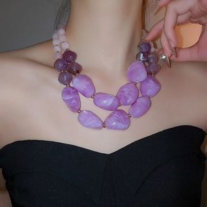 Close-up of double-layered beaded necklace with purple acrylic stones and gold accents