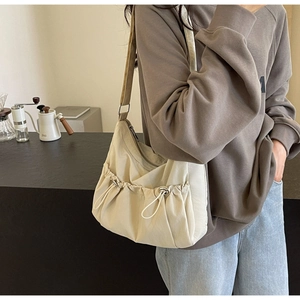 Detail view of cream nylon pleated crossbody bag featuring drawstring design
