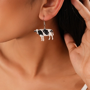 Close-up of cow print patterned earring worn by a model showcasing high-quality details