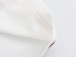 Detailed close-up of white fabric texture with delicate red fine line edge stitching
