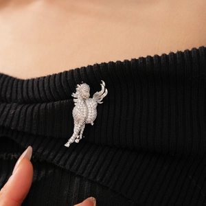 Macro detail of silver winged horse brooch featuring pavé set zircon on black knit fabric