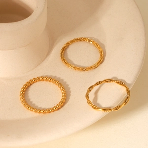 Macro shot of gold beaded, fine twist, and wavy rope twist stackable rings on ceramic