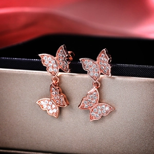 Close-up of rose gold bow earrings with cubic zirconia on pink silk backdrop