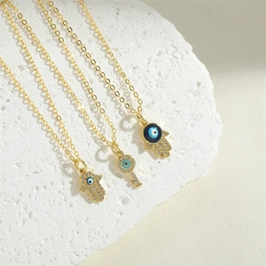 Golden Hamsa hand and key pendant necklaces with evil eye detail and crystals