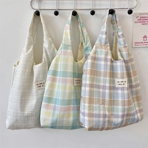 Close-up of three checkered canvas tote bags in green, blue, and purple on hooks