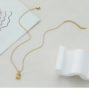 Detailed view of golden 18K gold-plated geometric bear pendant on a delicate bead chain