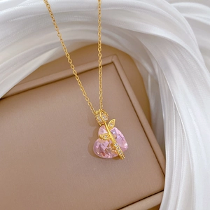 Close-up of pink heart gemstone necklace with gold rose and sparkling diamond accents