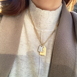 Gold plated stainless steel necklace with double pendants and shell starburst on a model