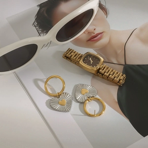 Golden square watch and heart pendant earrings set displayed on fashion magazine background
