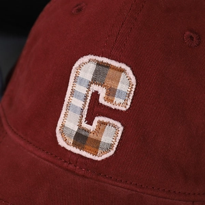 Macro detail of wine red baseball cap with vintage plaid C letter patch embroidery
