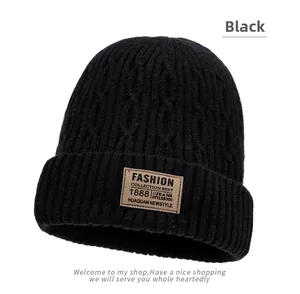 Close-up of black cable knit beanie with fleece lining and FASHION leather patch