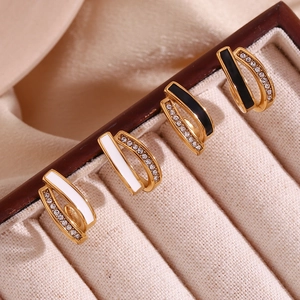 Detailed close-up of 18K gold plated U-shaped earrings with black white enamel and crystals