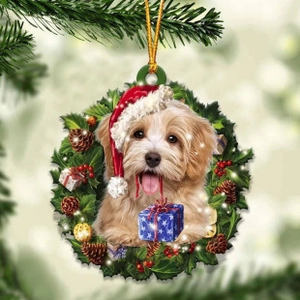 Close-up of a golden dog in a Christmas wreath ornament hanging on a pine tree branch