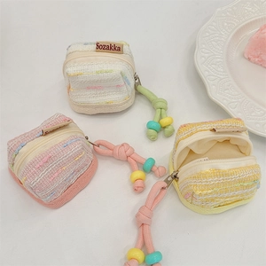 Detail of tweed fabric earphone case pouches in pastel colors with beaded zipper pulls
