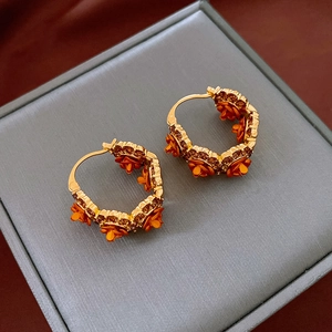 Gros plan de boucles d'oreilles fleurs en U dorées avec pierres jaunes sur coffret