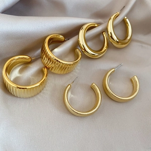 Macro detail of three pairs of gold-plated hoop earrings with textured and polished finishes