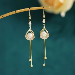 Detailed close-up of golden pearl tassel earrings with micro-set zircons and chain drops