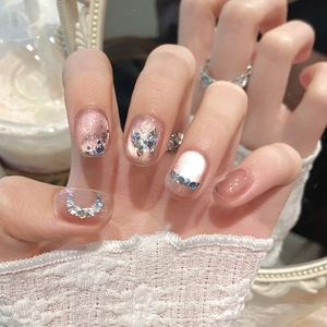Vue détaillée d'ongles cat-eye roses avec strass papillon et paillettes brillantes