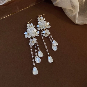 Close-up of elegant pearl tassel earrings with white shell flower details and gold finish