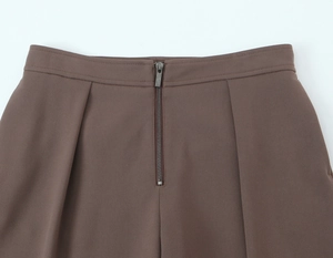 Gros plan détaillé de la fermeture éclair et du tissu sur un pantalon marron chic