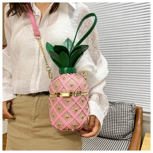Pink pineapple crossbody bag featuring gold studs and a realistic green leaf top handle