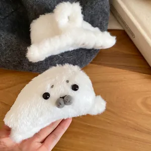 Cute white plush seal hair claw clip and minimalist fuzzy hair clip set on a wooden desk