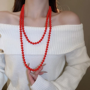 Detail of red faux pearl double layer long necklace on a white knit sweater