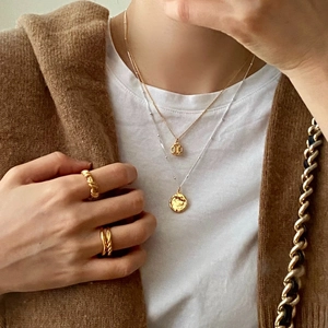Layered 925 sterling silver necklaces with textured coin pendants and twisted gold rings