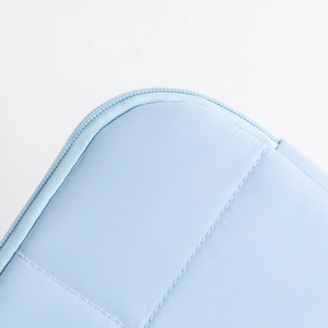 Detail of light blue laptop sleeve with rounded zipper closure and vertical quilting texture