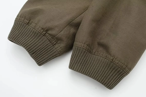 Close-up of olive green ribbed knit cuffs and smooth woven fabric on a bomber jacket