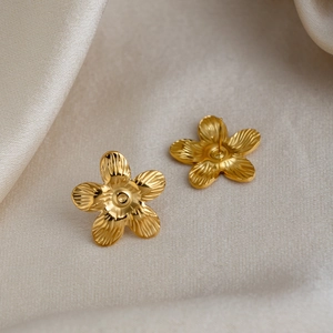 Macro view of gold flower earrings showing radial petal texture and 18K plated finish