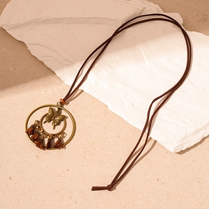 Detail of vintage bronze ring pendant with butterfly design and brown tassels