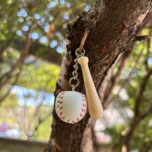 Miniature wooden baseball bat and leather ball keychain hanging on a tree branch