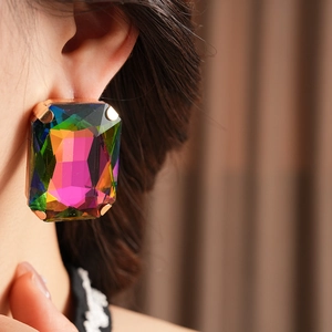 Close-up of a model wearing large vintage-style rectangular earrings with multi-color gems