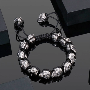 Macro detail of silver skull beads on a black braided rope bracelet with reflections
