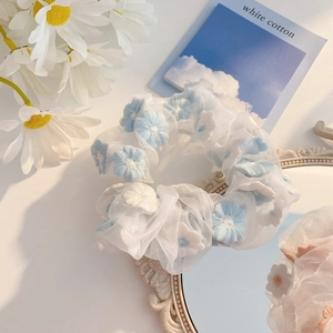 Macro shot of embroidered floral organza hair scrunchies with delicate daisy petals
