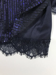 Detalle de lentejuelas azul marino y encaje negro en el dobladillo de un vestido de noche