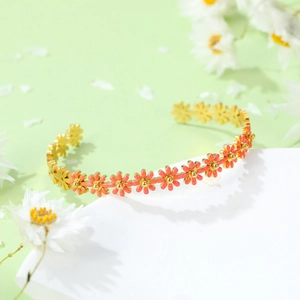 Golden titanium steel open bracelet featuring pink daisy enamel and floral accents