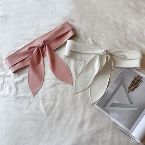 Vue détaillée des ceintures corset en cuir PU rose et blanc avec nœuds sur fond de tissu