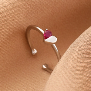 Detail of an open silver ring with a pink pear-cut zircon and heart-shaped metal accent
