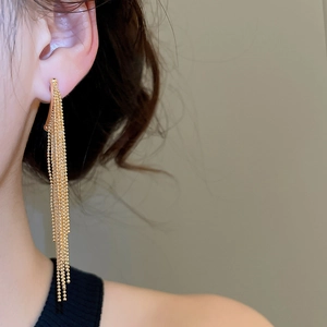 Detail shot of long gold-plated drop fringe earrings with beaded tassels on model